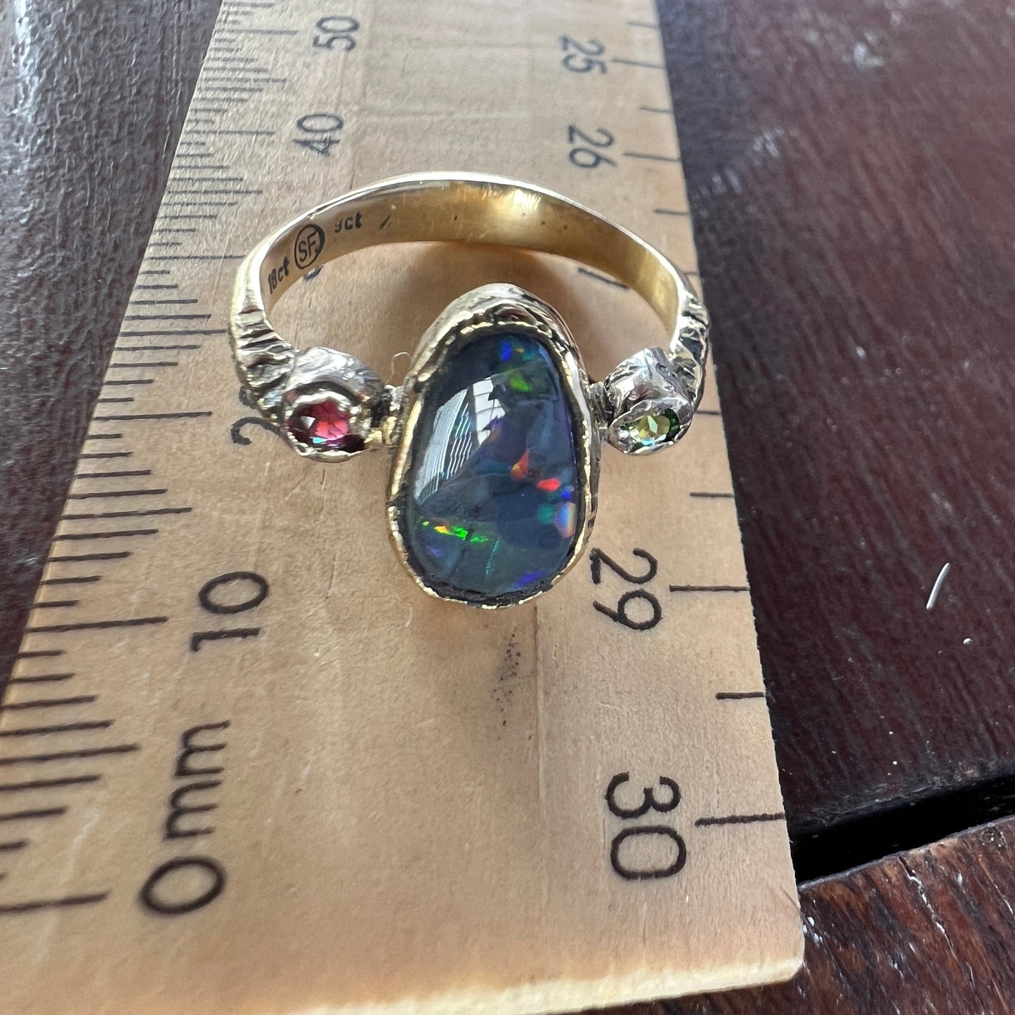 Perfect solid black opal from Lightning Ridge. Opal flanked with Burmese Spinel and Tsavorite. 18ct gold with 9ct gold mounts. Ring size N can be adjusted. This is as good as it gets for a Lightning Ridge black opal displaying all the colours. Magnificent.