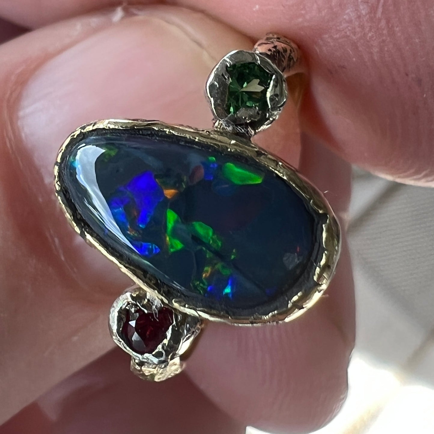 Perfect solid black opal from Lightning Ridge. Opal flanked with Burmese Spinel and Tsavorite. 18ct gold with 9ct gold mounts. Ring size N can be adjusted. This is as good as it gets for a Lightning Ridge black opal displaying all the colours. Magnificent.