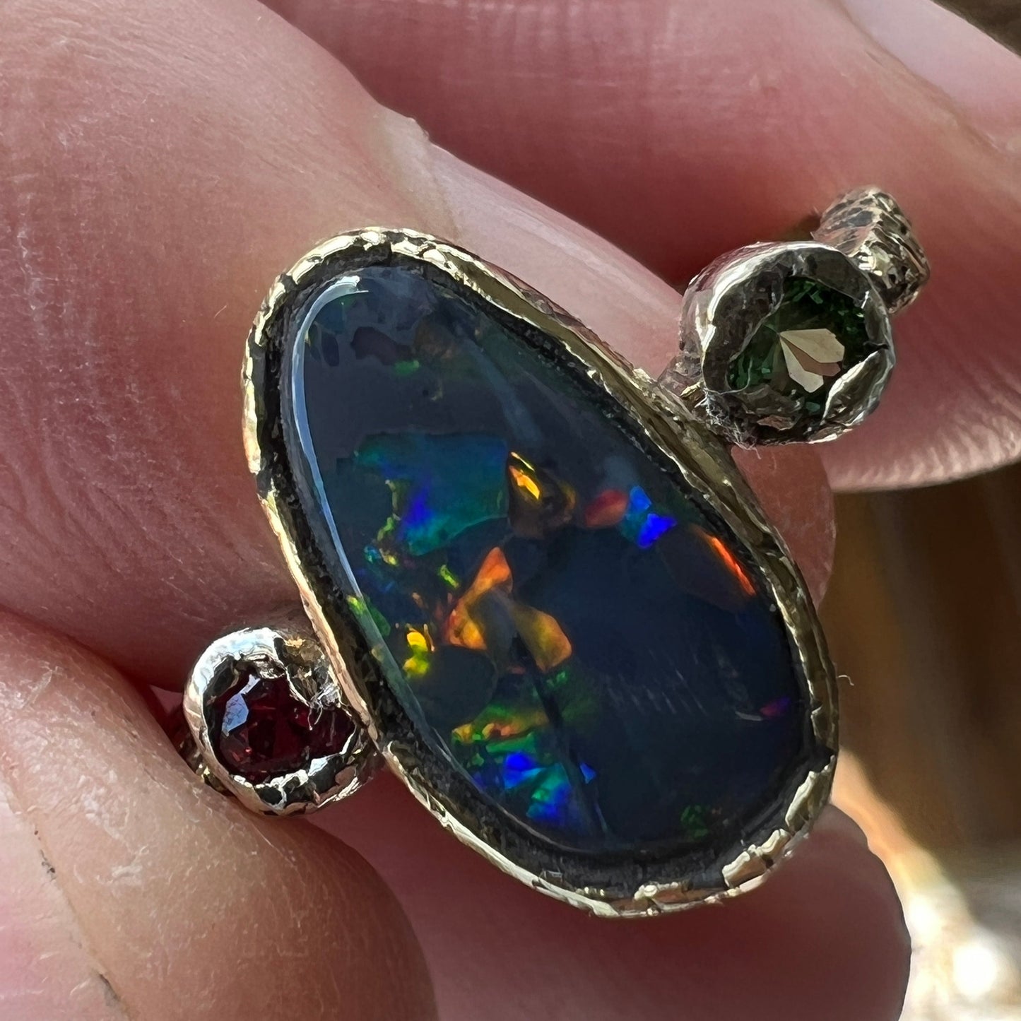 Perfect solid black opal from Lightning Ridge. Opal flanked with Burmese Spinel and Tsavorite. 18ct gold with 9ct gold mounts. Ring size N can be adjusted. This is as good as it gets for a Lightning Ridge black opal displaying all the colours. Magnificent.