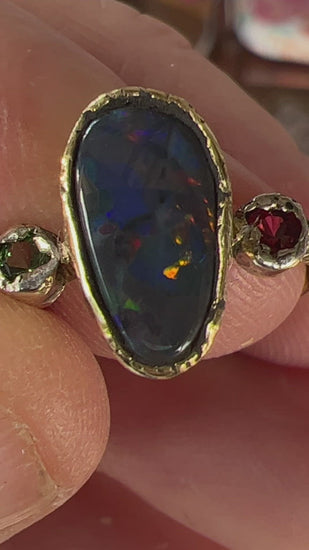 Perfect solid black opal from Lightning Ridge. Opal flanked with Burmese Spinel and Tsavorite. 18ct gold with 9ct gold mounts. Ring size N can be adjusted. This is as good as it gets for a Lightning Ridge black opal displaying all the colours. Magnificent.
