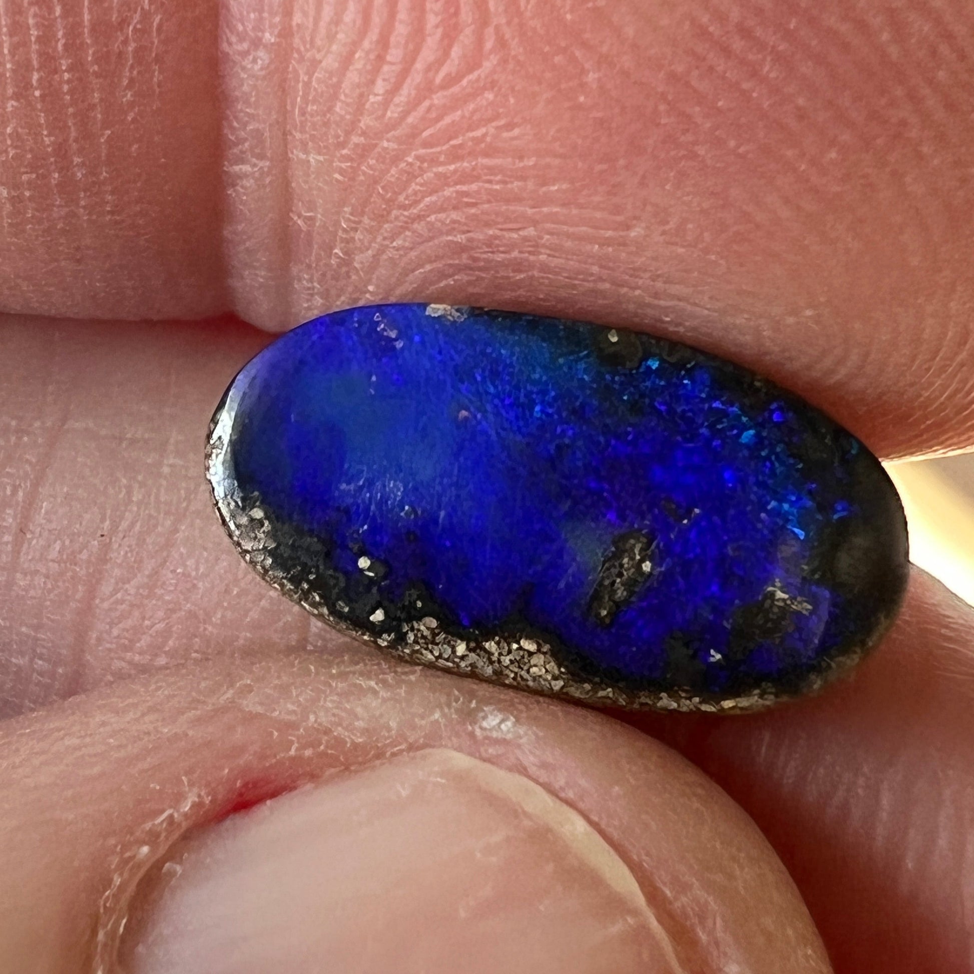 A great shaped little boulder opal with bright blues.