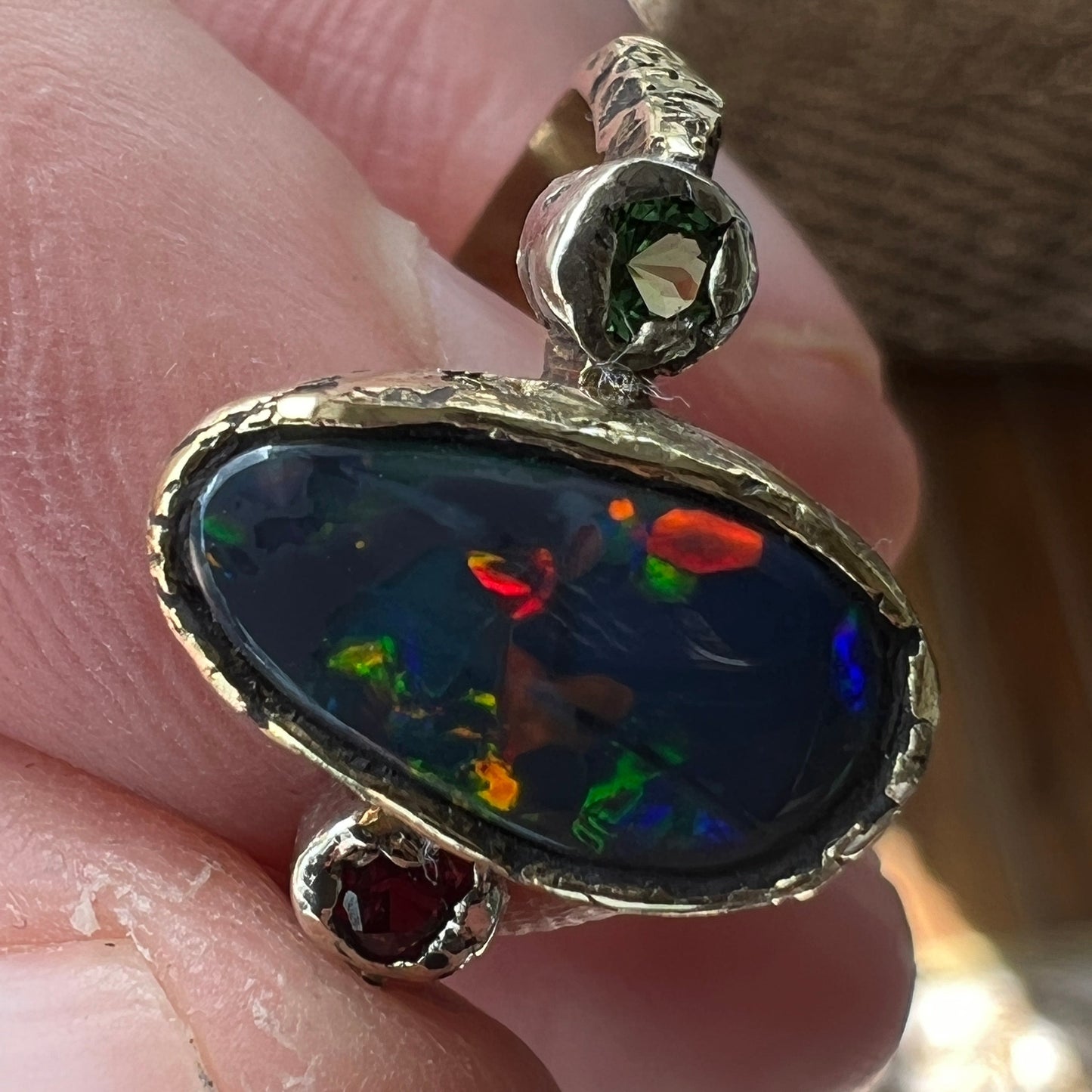 Perfect solid black opal from Lightning Ridge. Opal flanked with Burmese Spinel and Tsavorite. 18ct gold with 9ct gold mounts. Ring size N can be adjusted. This is as good as it gets for a Lightning Ridge black opal displaying all the colours. Magnificent.