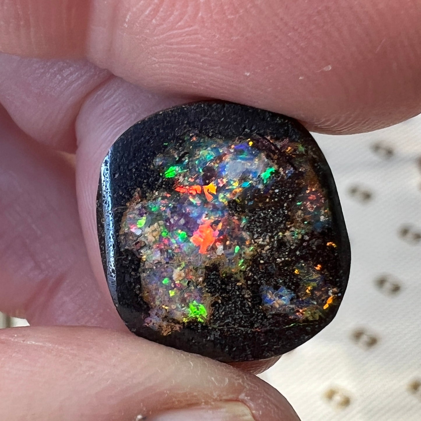Nice round boulder opal displaying a multitude of colours including reds, blues and greens.